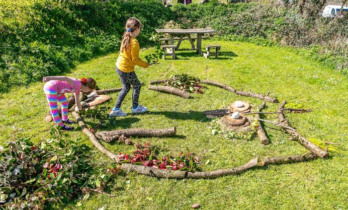 Two children doing outside crafts with leaves and branches